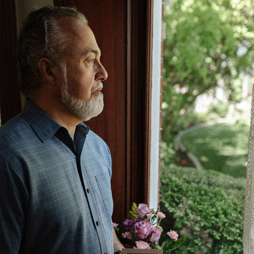 Man standing by a window looking outside with a garden view