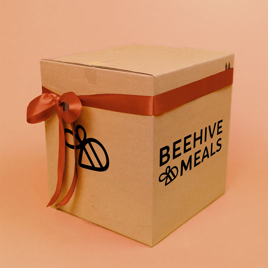 Cardboard box with a red ribbon and 'Beehive Meals' logo on a peach background