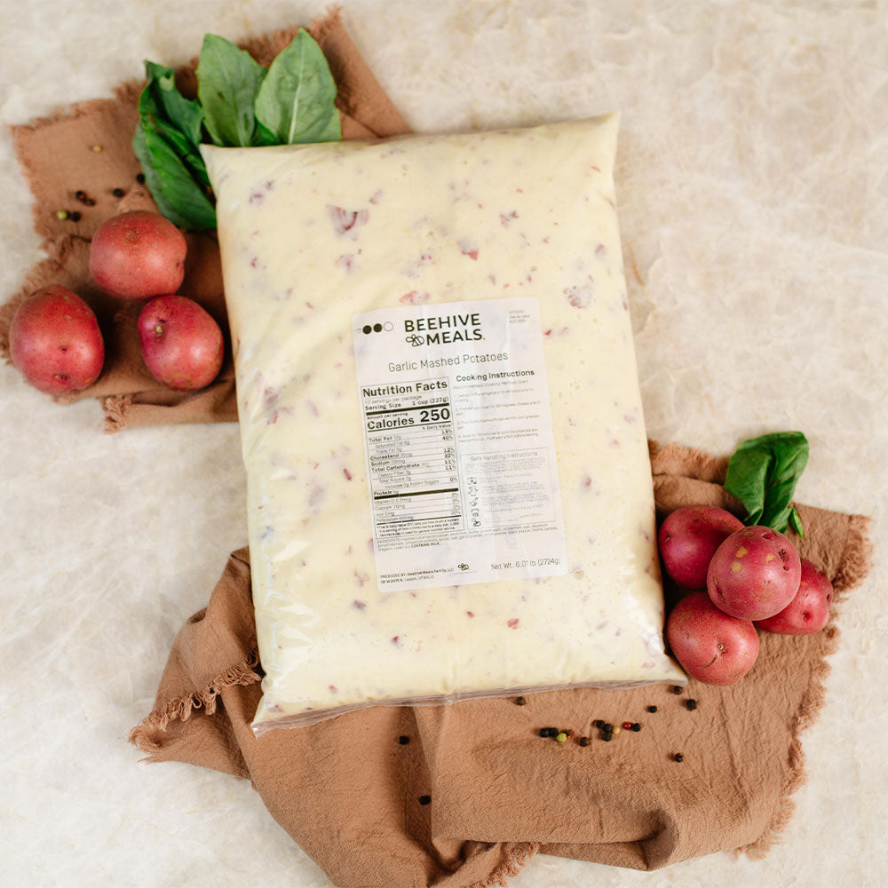 Package of Beehive Meals Garlic Mashed Potatoes with potatoes and spinach on a textured surface
