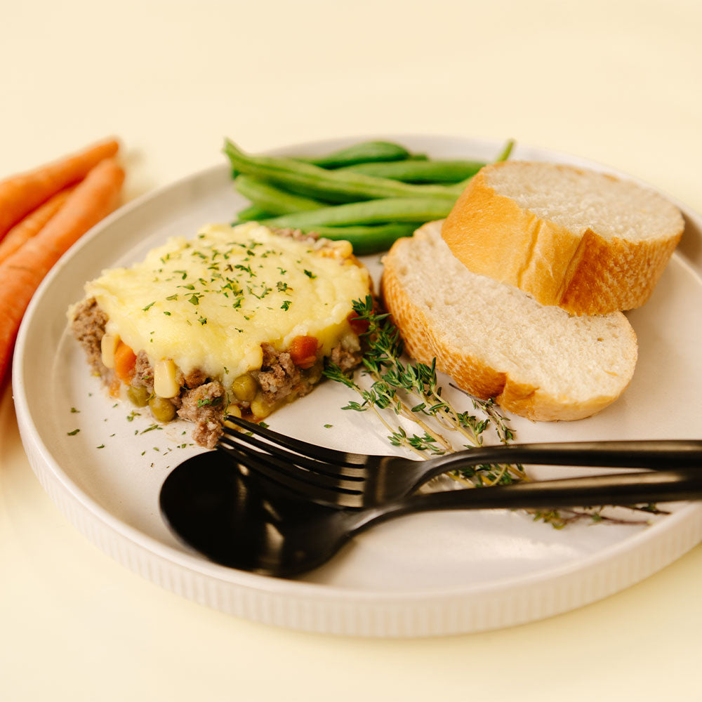 Shepherd's pie with vegetables and bread on a plate