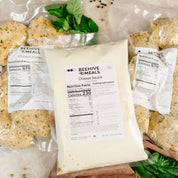 Packaged cheese sauce with Beehive Meals branding and nutritional information, surrounded by other food items.
