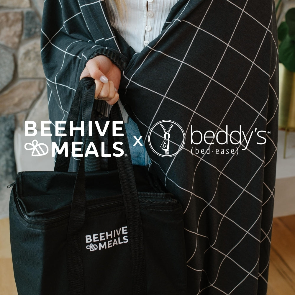 Person holding a black bag with 'Beehive Meals' logo, featuring Beddy's (bed-ease) logo and Charcoal Grid On-The-Go Blanket