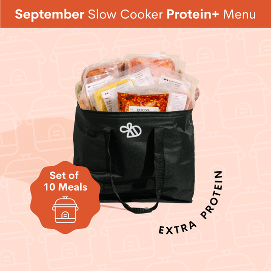 A black insulated slow cooker bag filled with packaged protein meals, shown on a pale pink patterned background with promotional text reading 'September Slow Cooker Protein+ Menu' and 'Set of 10 Meals'.