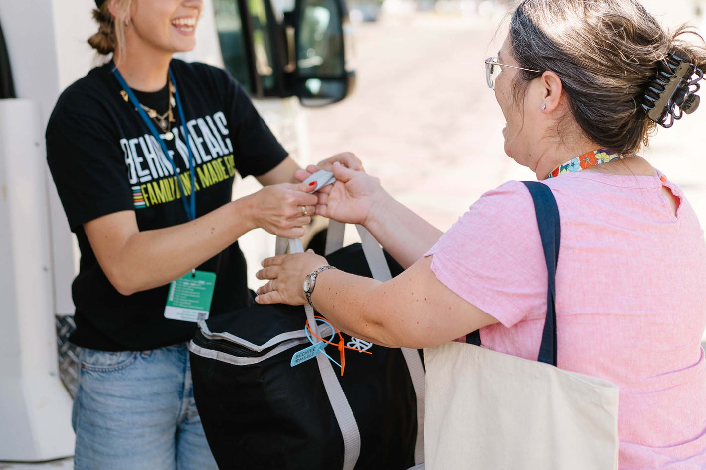 Employee handing a set of Beehive Meals to a teacher