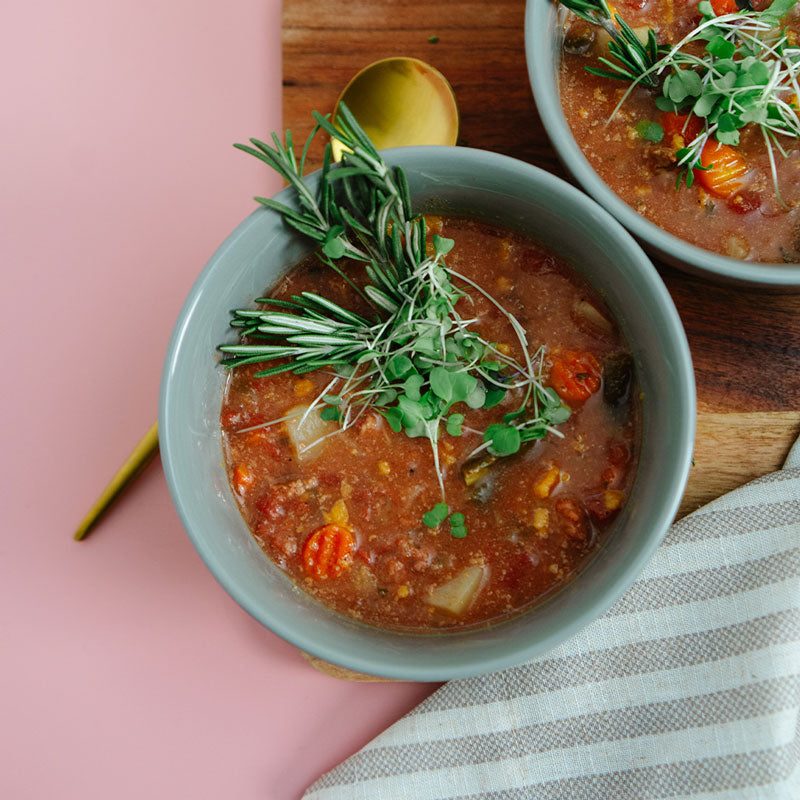 Bowl of soup with garnishes on a pink surface