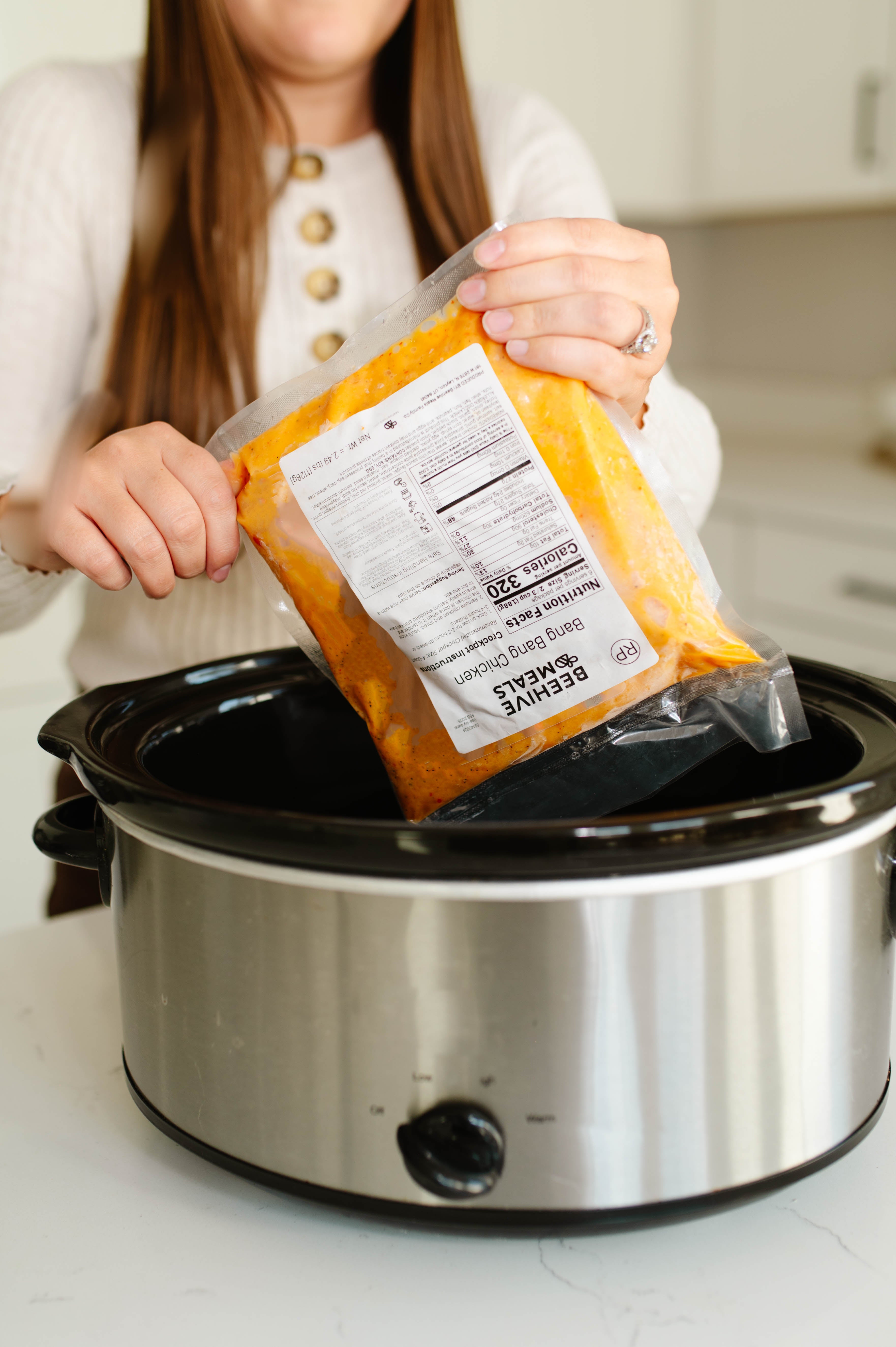 Women placing Beehive Meals Bang Bang Chicken into a slow cooker