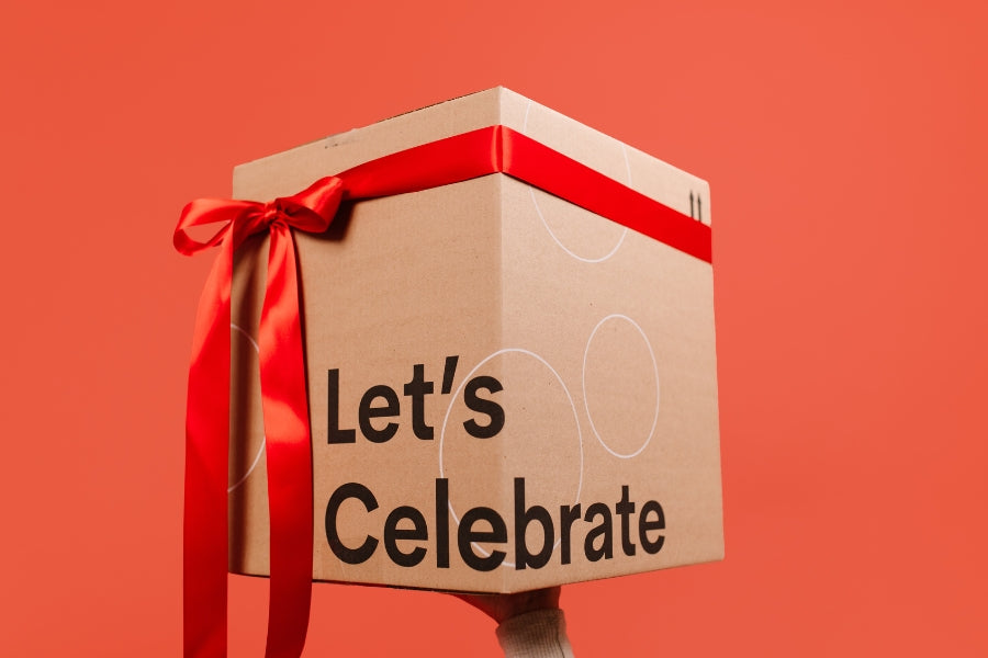 Beehive Meals Gift Box with 'Let's Celebrate' text and red ribbon on a red background