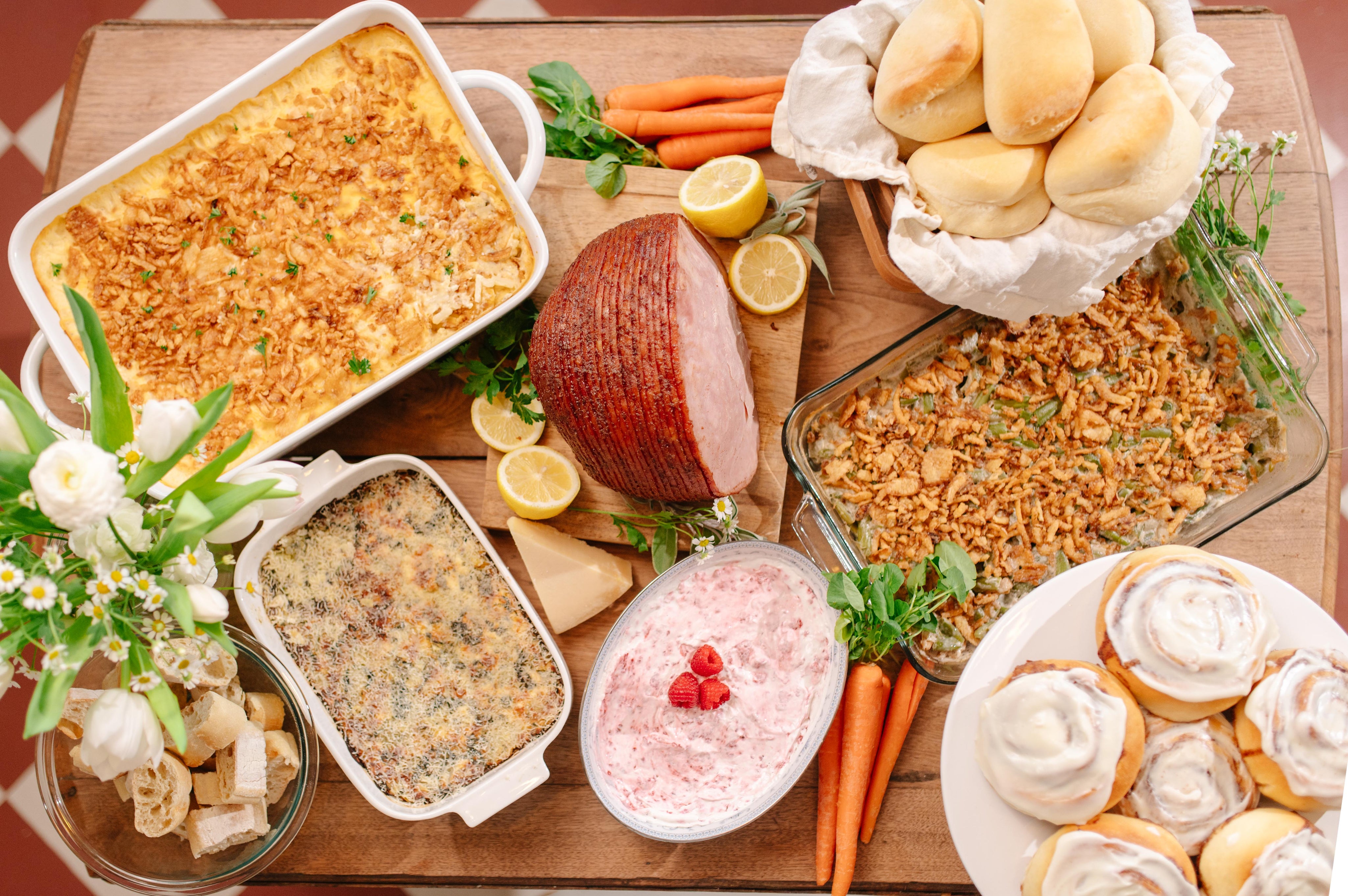 Assorted Easter dinner including a ham, carrots, and various casseroles on a wooden table.