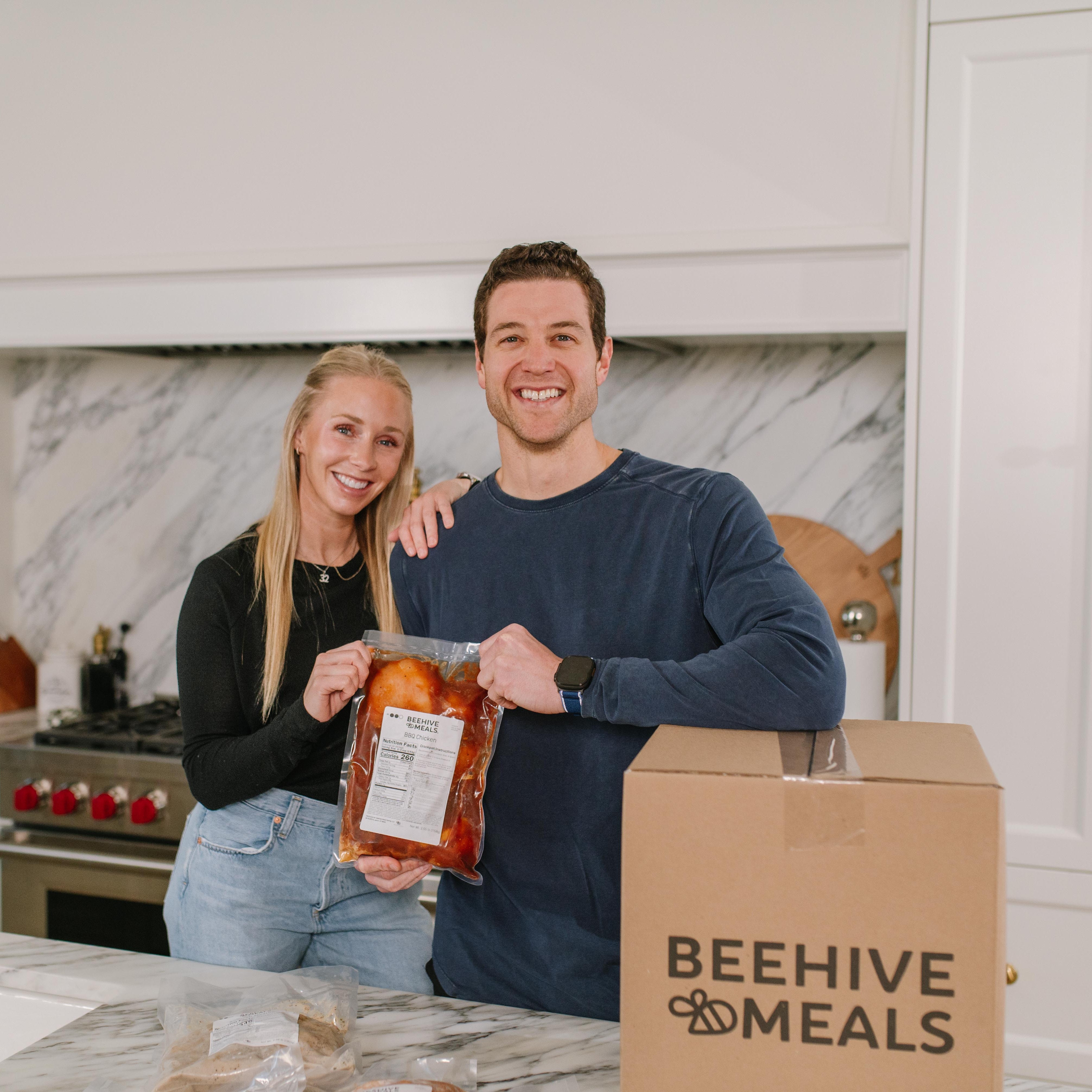 Jimmer & Whitney Fredette holding Beehive Meals BBQ Chicken in their kitchen